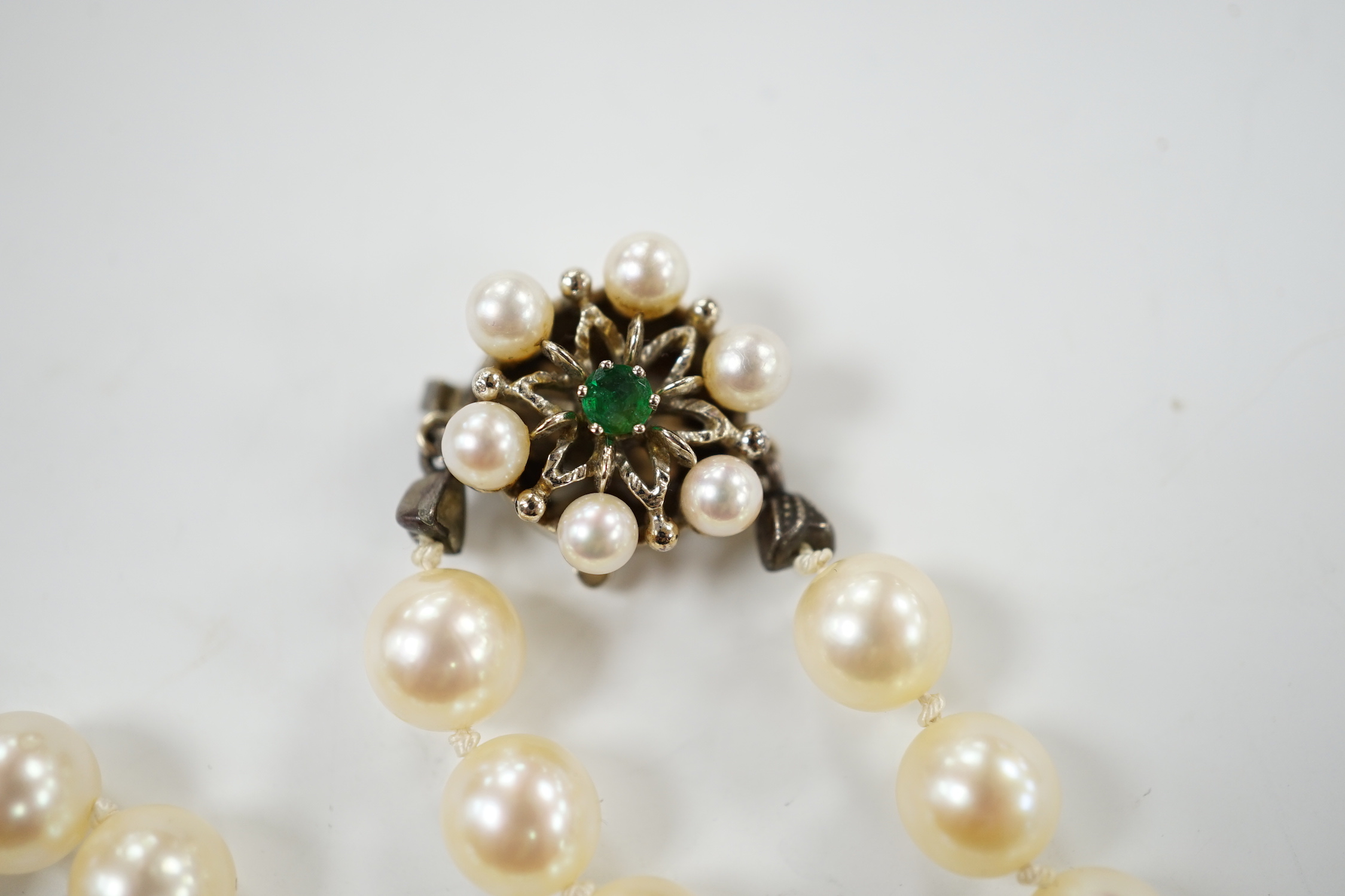 A single strand cultured pearl necklace, with cultured pearl and emerald set 585 yellow metal clasp, 49cm.